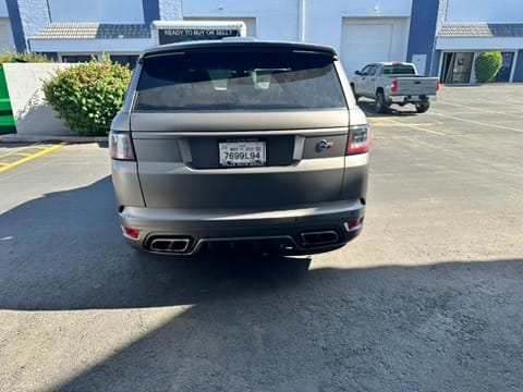 Rear view of a silver SUV parked in a lot with blue buildings in the background.