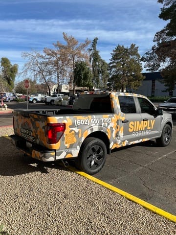 Branded Simply Roofing pickup truck parked in a lot, gray camouflage wrap with logo and phone number on the side.