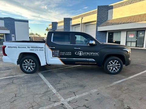 Black-and-white pickup truck in a parking lot advertising catastrophic injury lawyers; side reads 'Start Your Case Today' and 'Attorney Access, No Middleman' for contact information.