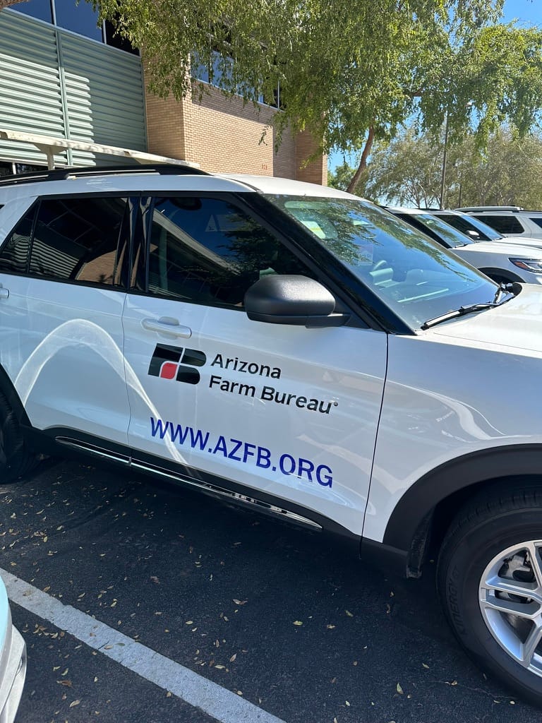 White SUV displaying Arizona Farm Bureau branding and the website www.azfb.org in a parking lot. (informational)