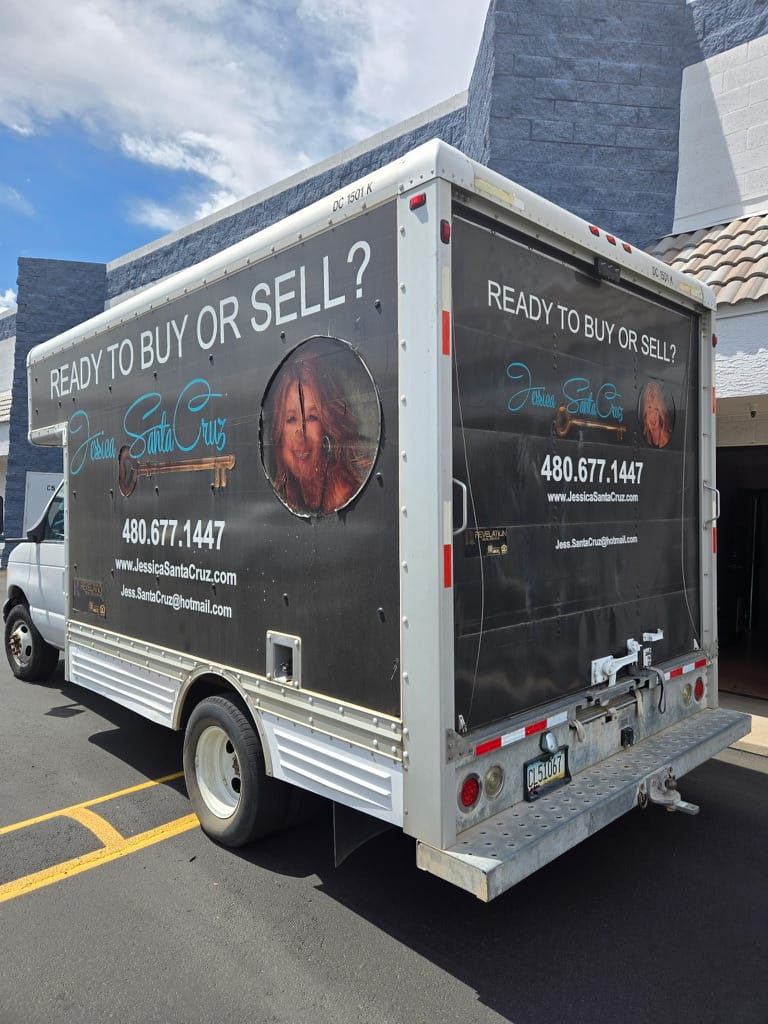 Promotional box truck advertising real estate services for Jessica Santa Cruz with the slogan 'Ready to buy or sell?' and contact info on black panels